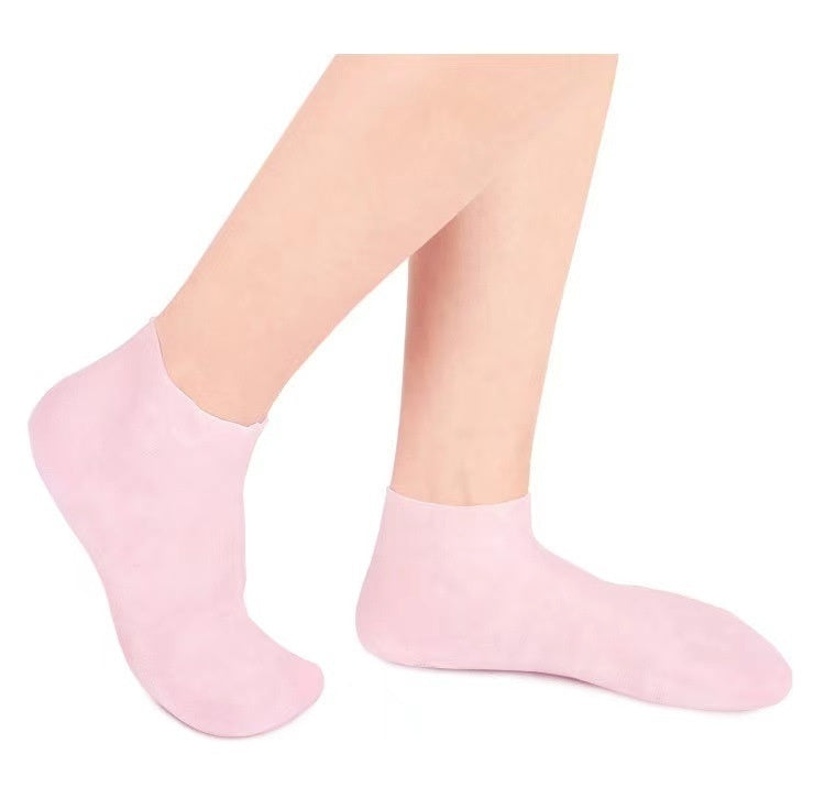 Gel moisturizing silicone socks in light pink worn on feet, ideal for healing cracked heels and enhancing lotion absorption indoors.